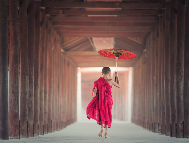A photo of a young boy in red garb holding a paper parasol