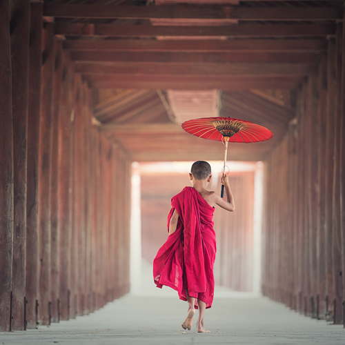 A photo of a young boy in red garb holding a paper parasol