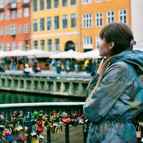 A photo of a girl standing on the Bryggebroen, where many padlocks can be seen on the bridge