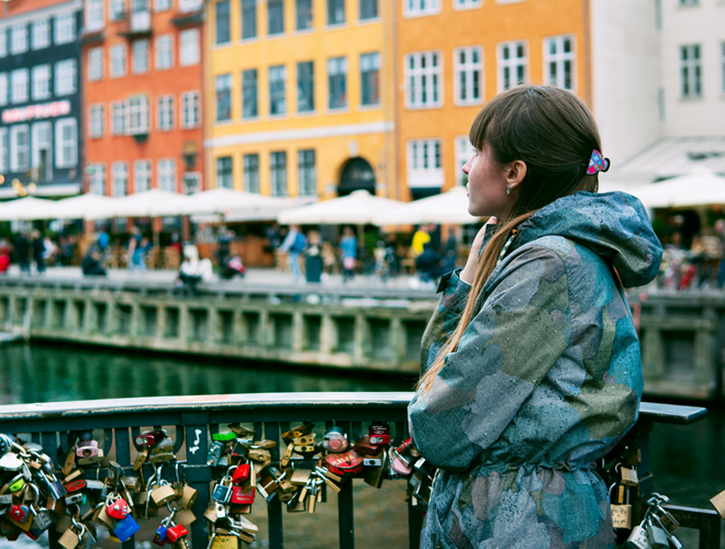 A photo of a girl standing on the Bryggebroen, where many padlocks can be seen on the bridge